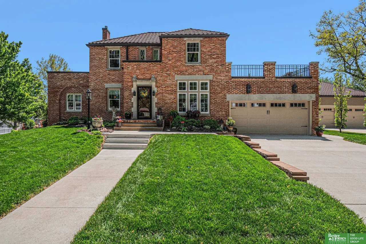 Two-story brick home with a rooftop terrace, double garage, and landscaped front lawn.